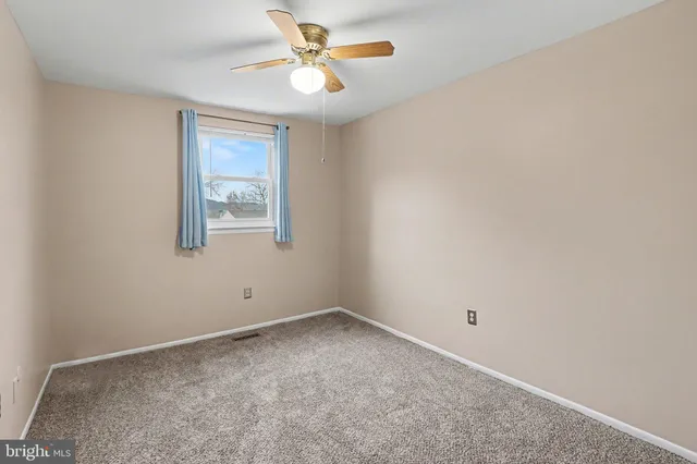 an empty room with a chandelier fan and closet