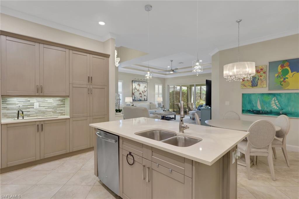5752 Elbow Avenue Naples, FL 34113 - Photo 38 of 38 Kitchen featuring ornamental molding, open floor plan, a kitchen island with sink, a tray ceiling, and stainless steel dishwasher