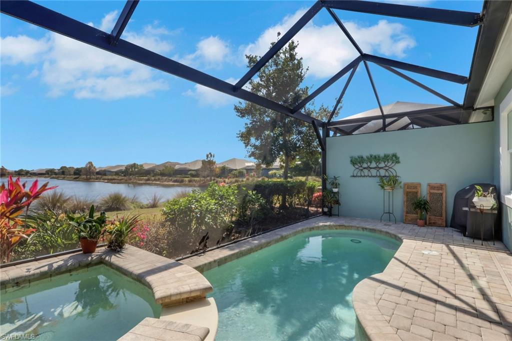 5752 Elbow Avenue Naples, FL 34113 - Photo 22 of 38 Swimming pool with glass enclosure, a patio area, a sunroom, a residential view, and a water view