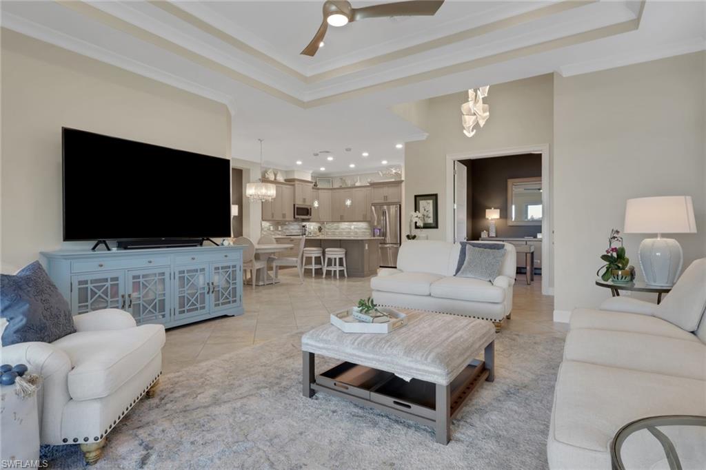 5752 Elbow Avenue Naples, FL 34113 - Photo 5 of 38 Living area with ceiling fan, ornamental molding, light tile patterned flooring, a chandelier, and a tray ceiling
