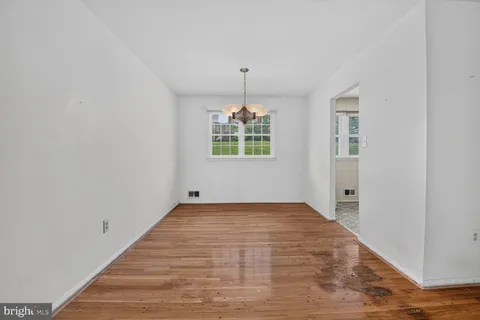 a view of an empty room with window and chandelier fan