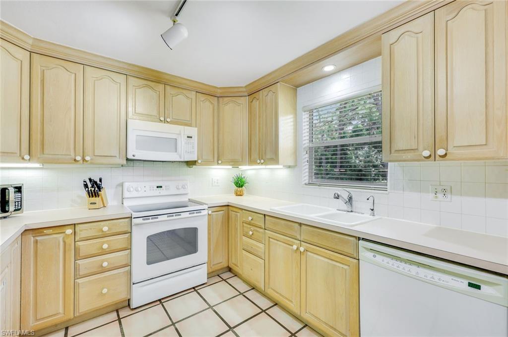 131 Cajeput Drive Naples, FL 34108 - Photo 10 of 30 a kitchen with white cabinets and white appliances