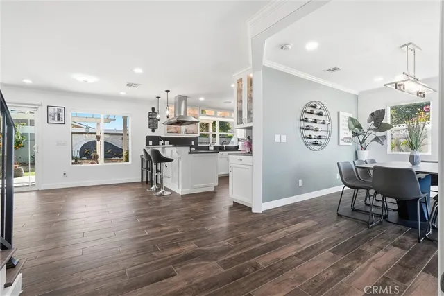 a kitchen with stainless steel appliances a dining table chairs and wooden floor