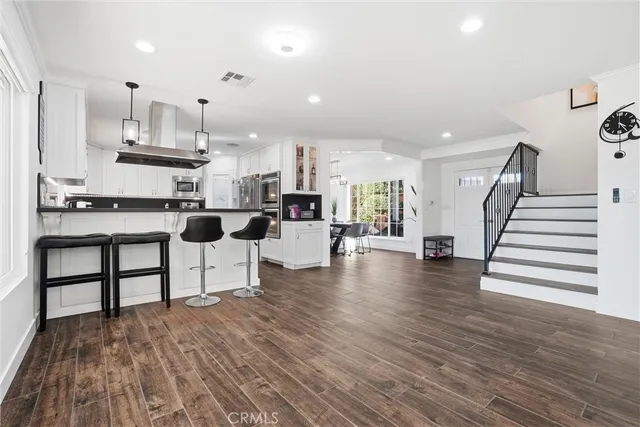 a kitchen with stainless steel appliances kitchen island wooden floors and white cabinets
