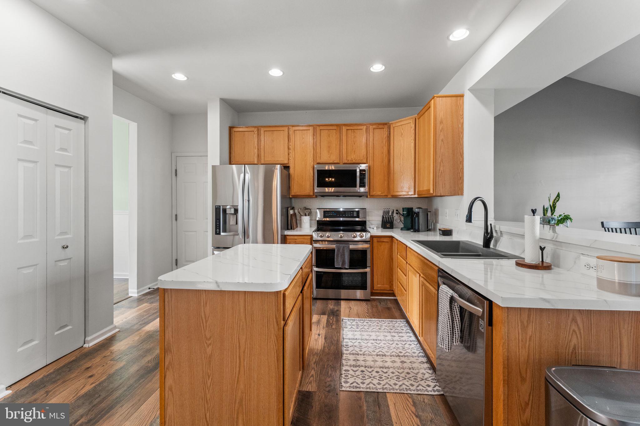 5219 Joshua Tree Circle Fredericksburg, VA 22407 - Photo 7 of 42 a kitchen with stainless steel appliances granite countertop a stove top oven a sink dishwasher and a refrigerator with wooden floor