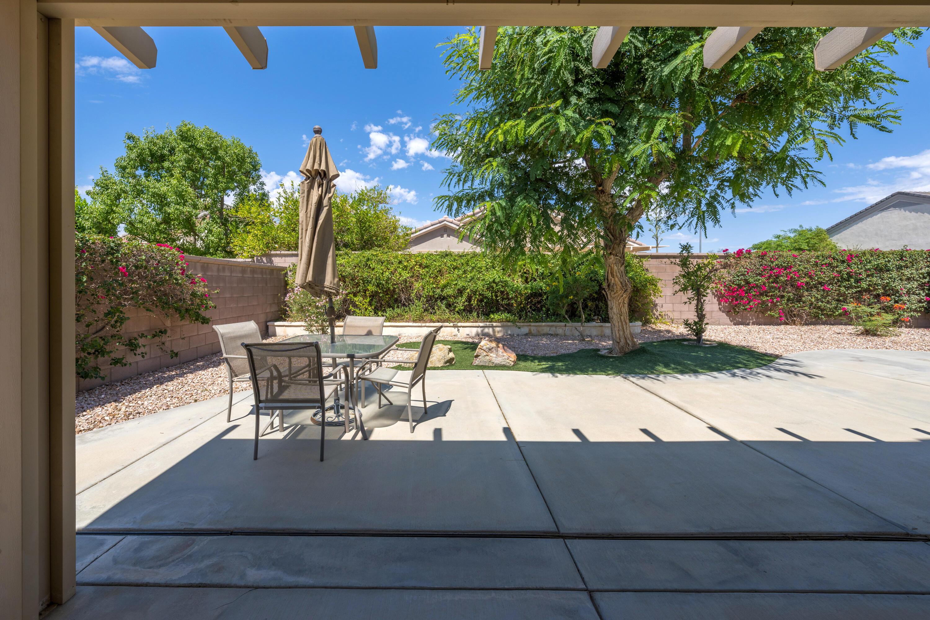 36403 Monarch Pass Palm Desert, CA 92211 - Photo 3 of 32 a view of a patio with dining table and chairs with a small yard