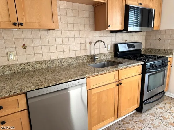 a kitchen with granite countertop white cabinets stainless steel appliances and a counter space