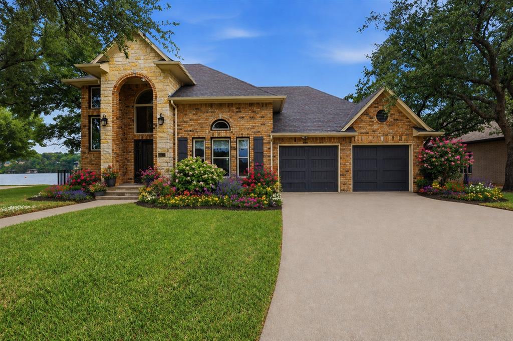 2406 River Road Granbury, TX 76048 - Photo 2 of 40 Brick and stone facade residence featuring a prominent arched entryway. Landscape around home and driveway have been digitally enhanced
