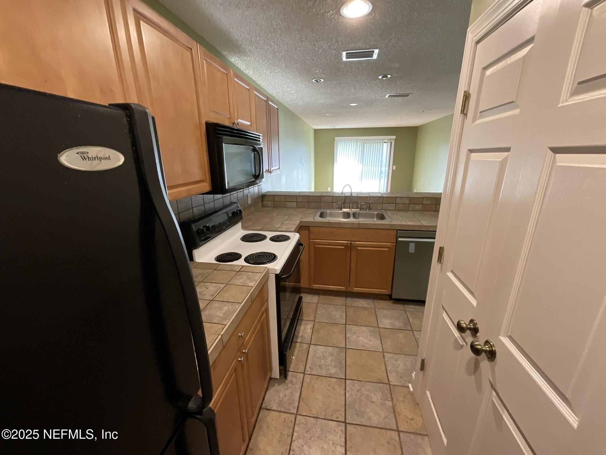 650 West Pope Road, Unit 252 St. Augustine, FL 32080 - Photo 15 of 33 a kitchen with a sink a stove top oven a refrigerator and a window