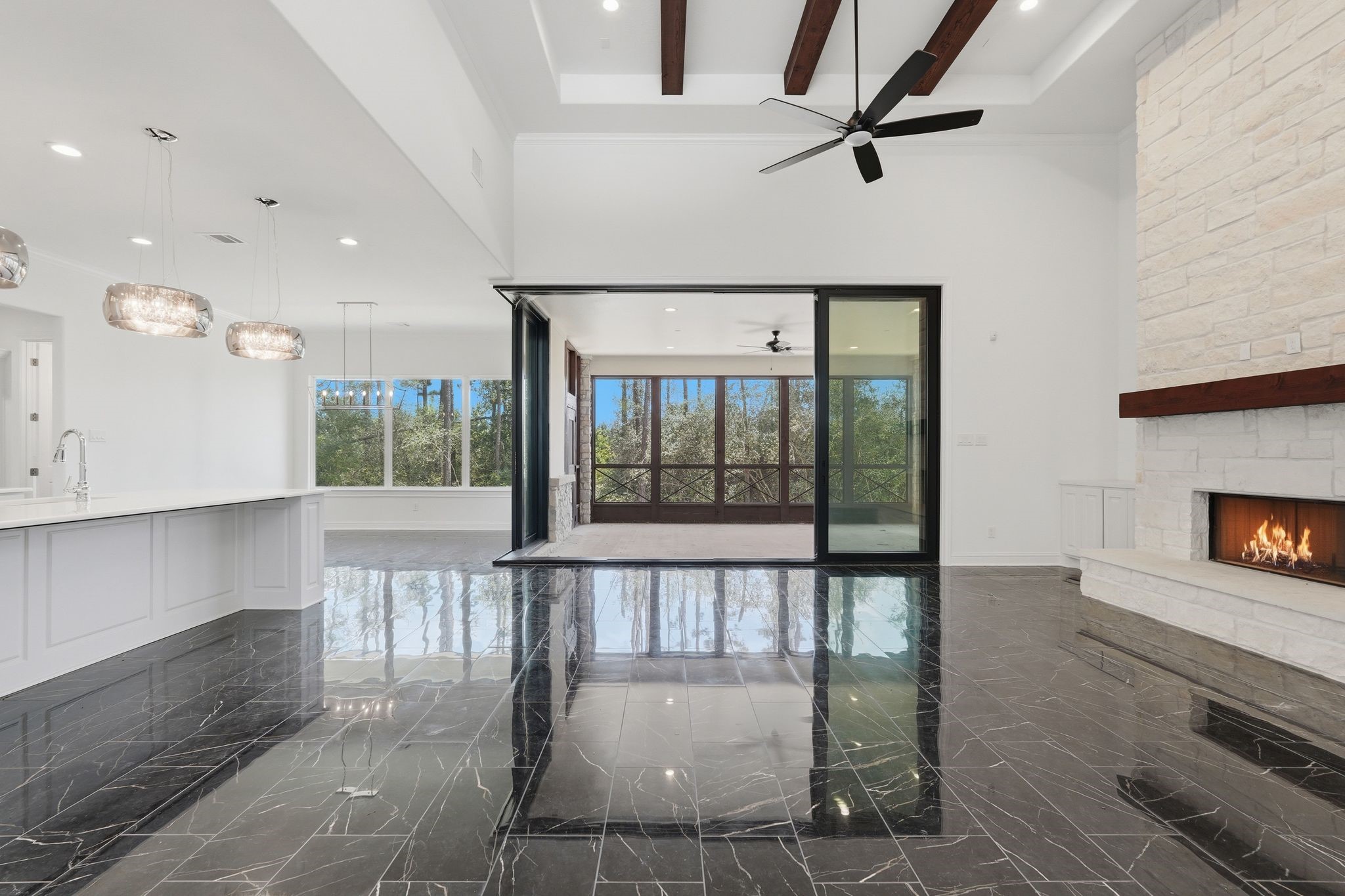 16081 Forest Mill Road Willis, TX 77378 - Photo 8 of 37 Wall-to-wall glass doors open to the screened porch, blending luxurious indoor living with peceful outdoor views.