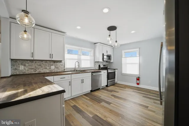 a kitchen with granite countertop a sink cabinets stainless steel appliances and a window