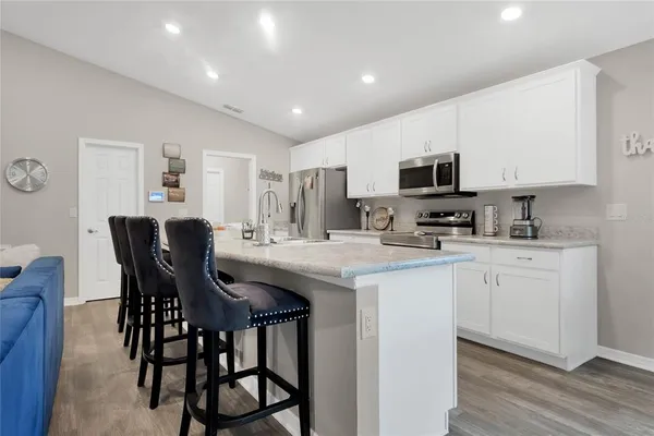 a kitchen with kitchen island granite countertop a table chairs microwave and cabinets