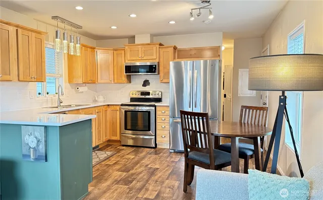 a kitchen with stainless steel appliances a sink a stove a refrigerator cabinets and a dining table