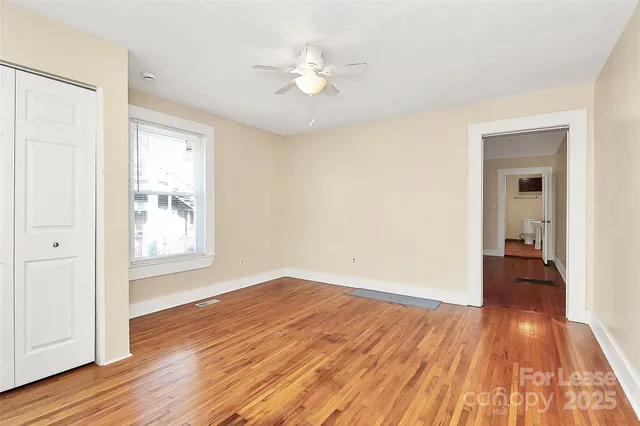 a view of a room with wooden floor and a ceiling fan