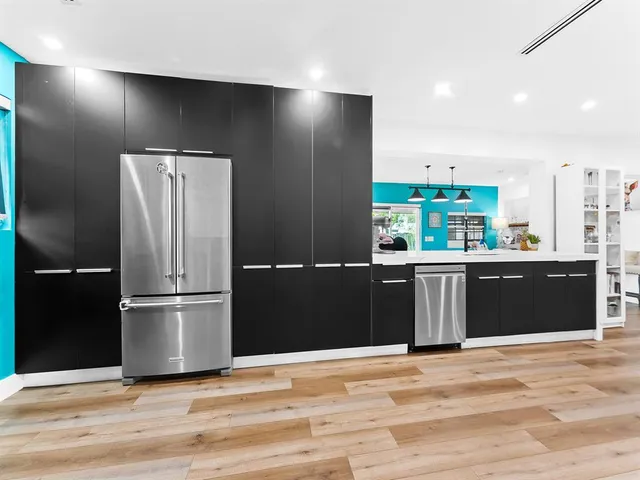 a kitchen with granite countertop a refrigerator cabinets and wooden floor