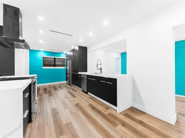 a large kitchen with stainless steel appliances a large counter top a stove and a sink