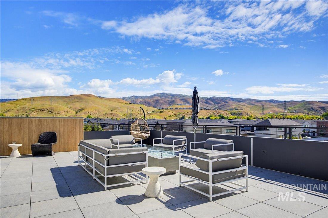 4184 East Haystack Street, Unit 103 Boise, ID 83716 - Photo 16 of 27 Spacious rooftop patio featuring large format tile flooring, a wood-finish privacy wall, and a low-profile dark gray perimeter wall