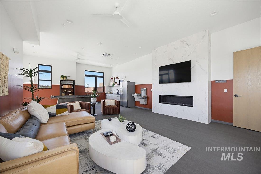 4184 East Haystack Street, Unit 103 Boise, ID 83716 - Photo 18 of 27 Spacious common area featuring a modern linear fireplace with a marble-finish surround, recessed kitchen area, dark wood-finish flooring, and multiple windows providing natural light
