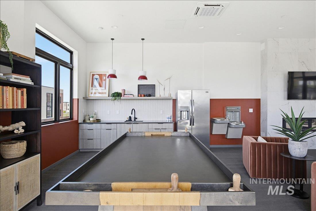 4184 East Haystack Street, Unit 103 Boise, ID 83716 - Photo 20 of 27 Spacious common area featuring a bocce ball court, built-in shelving, a full kitchen with stainless steel appliances, a fireplace with a stone surround, and large windows