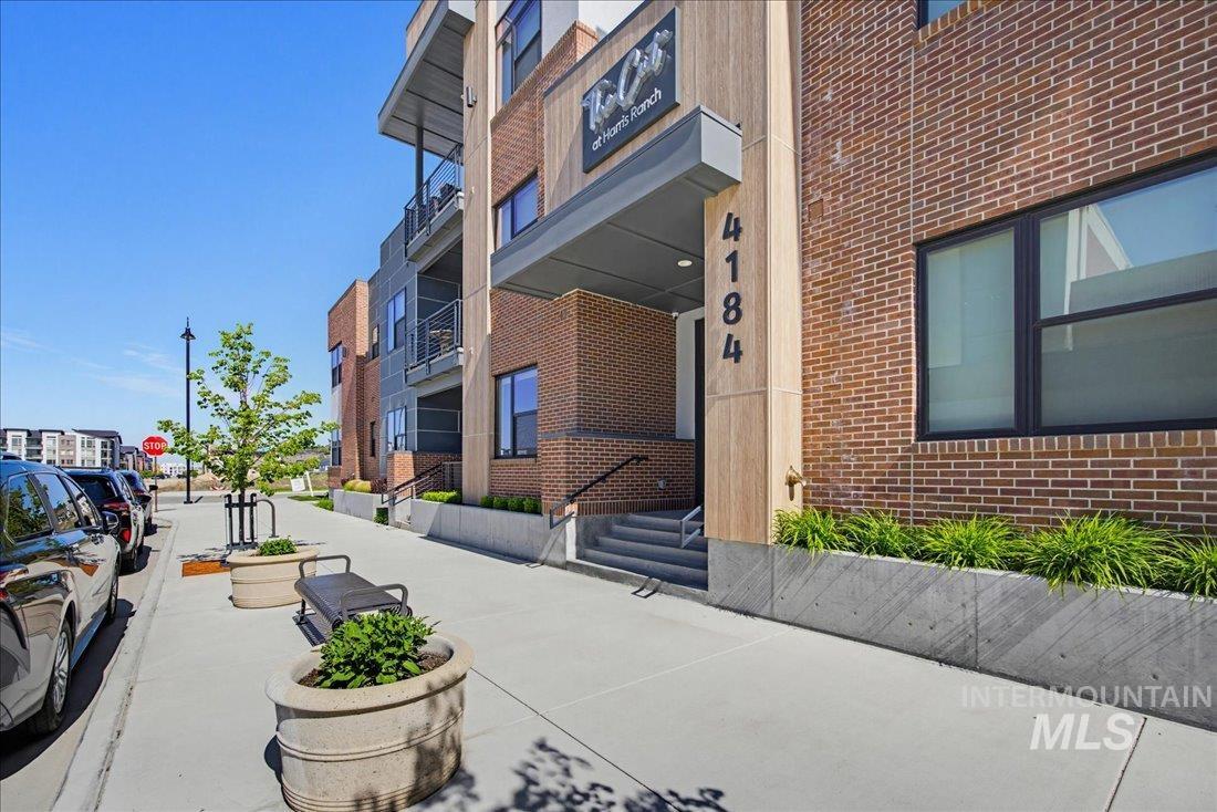 4184 East Haystack Street, Unit 103 Boise, ID 83716 - Photo 2 of 27 Contemporary multi-story building featuring a brick facade, wood-finish paneling, and large windows