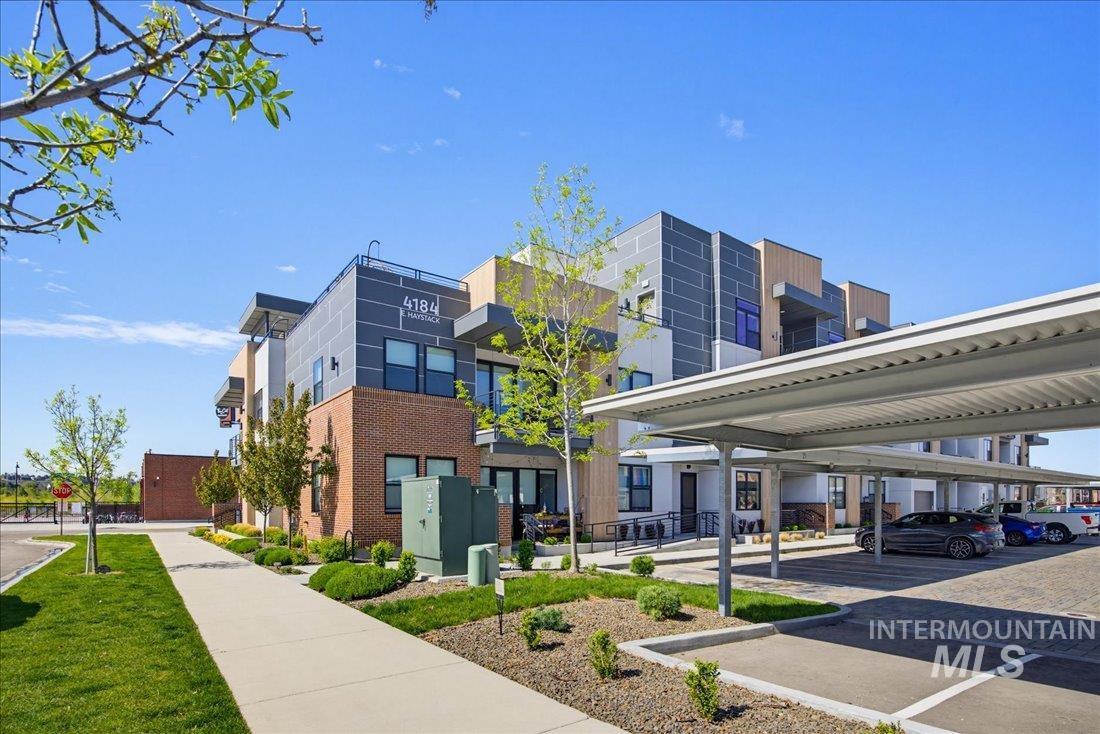 4184 East Haystack Street, Unit 103 Boise, ID 83716 - Photo 23 of 27 Contemporary multi-story building featuring brick and paneling accents, covered parking, and manicured landscaping