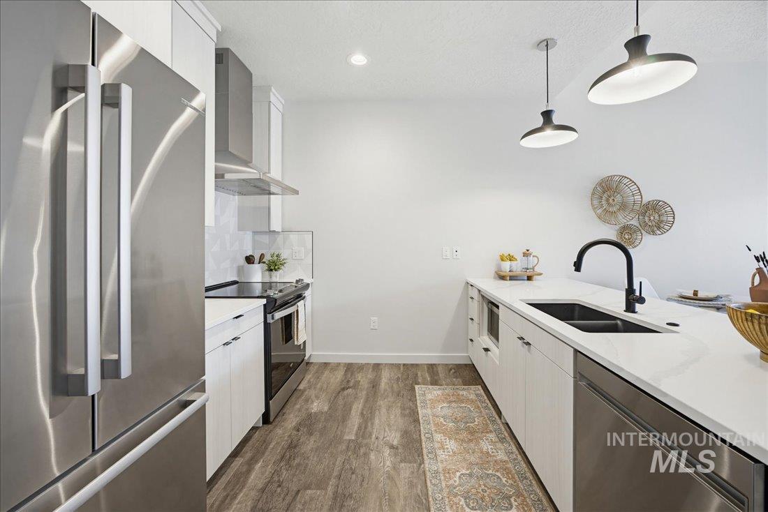 4184 East Haystack Street, Unit 103 Boise, ID 83716 - Photo 6 of 27 Kitchen featuring stainless steel appliances, wood-finish flooring, white cabinetry, a black sink, and pendant lighting