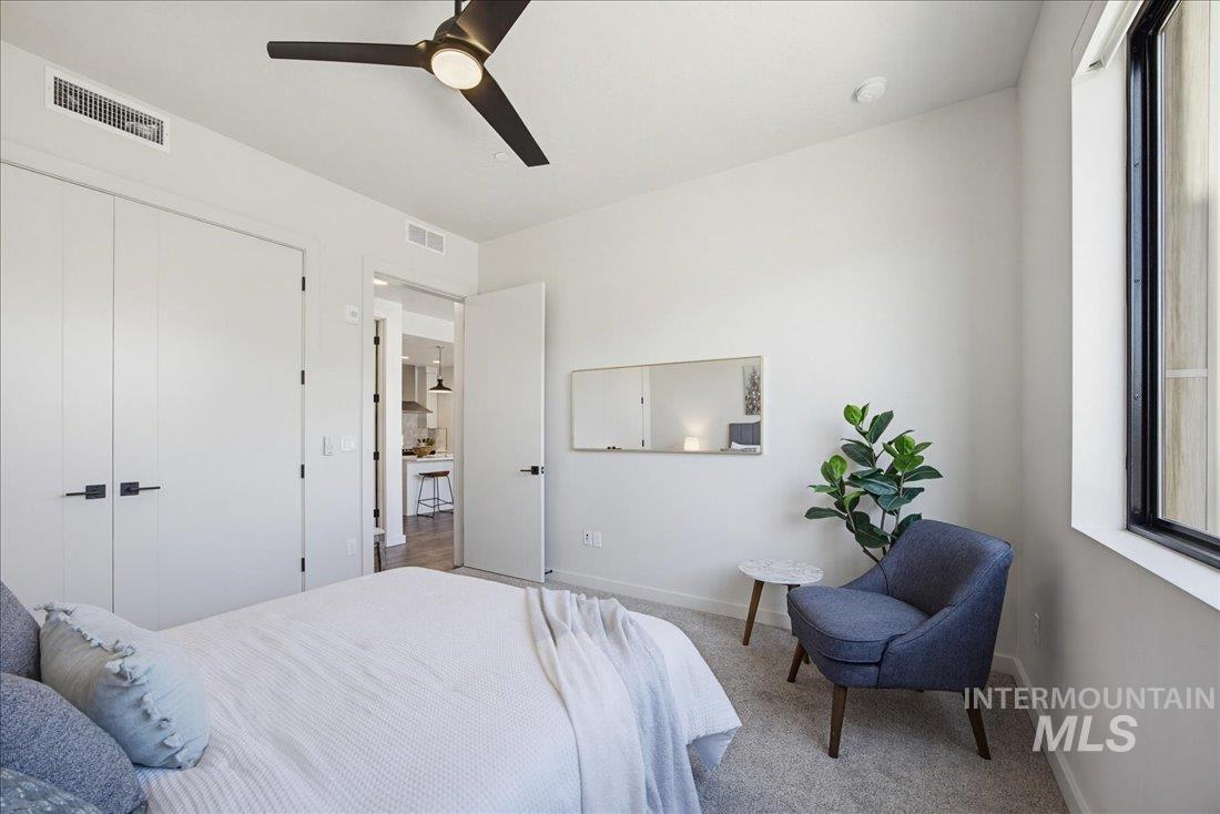 4184 East Haystack Street, Unit 103 Boise, ID 83716 - Photo 10 of 27 Light-filled room featuring large windows, a ceiling fan with integrated lighting, built-in closet storage with contemporary hardware, and light neutral-toned carpeting