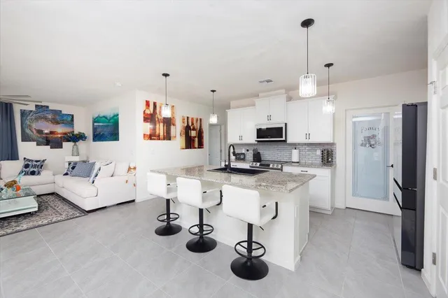 a kitchen with stainless steel appliances kitchen island granite countertop a sink a refrigerator and a granite counter tops