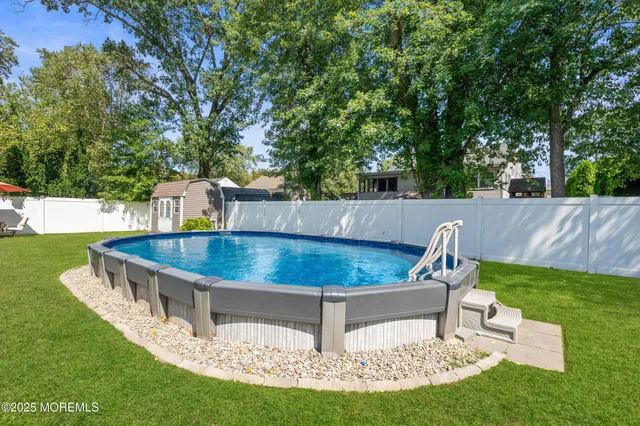 a view of a backyard with table and chairs potted plants and large tree