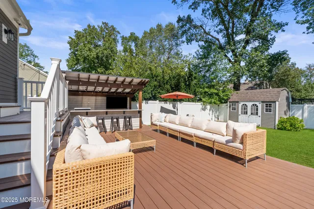 a view of a patio with couches table and chairs and potted plants with wooden floor and fence