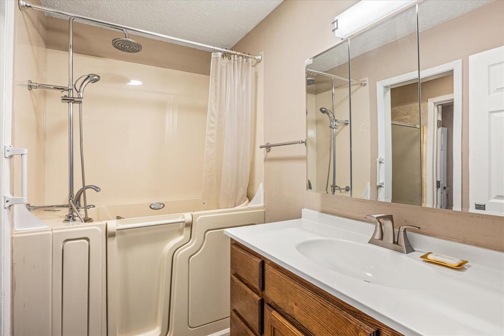246 Comanche Trail Weatherford, TX 76087 - Photo 9 of 37 a bathroom with a granite countertop sink a mirror and a shower