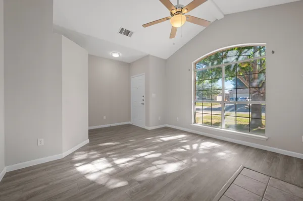 a view of an empty room with a window and wooden floor