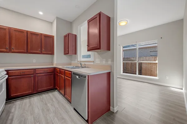 a kitchen with stainless steel appliances granite countertop wooden cabinets a sink and dishwasher with wooden floor