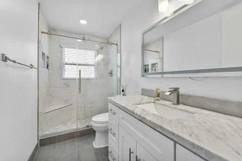 a bathroom with a granite countertop sink mirror vanity and toilet