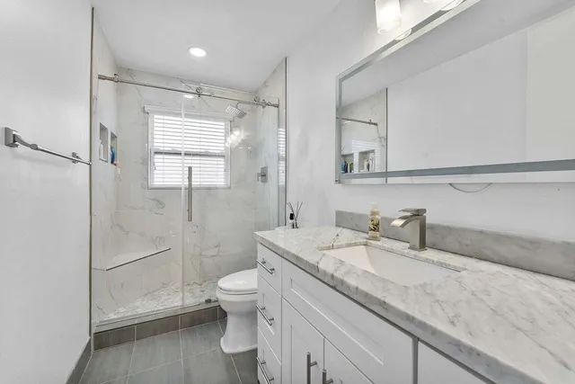 a bathroom with a granite countertop sink mirror vanity and toilet