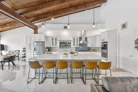 a kitchen with stainless steel appliances kitchen island granite countertop a dining table chairs and a oven