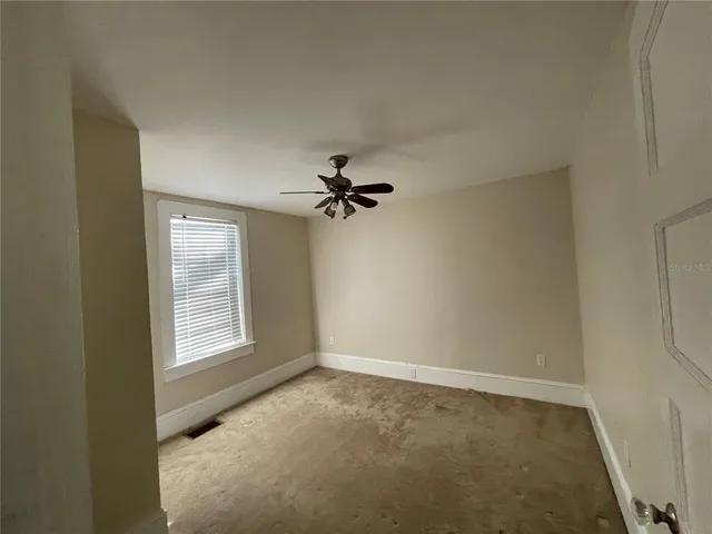 an empty room with windows and fan