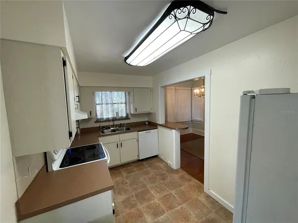 a large white kitchen with a stove a refrigerator and a window