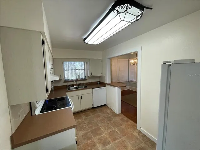 a large white kitchen with a stove a refrigerator and a window
