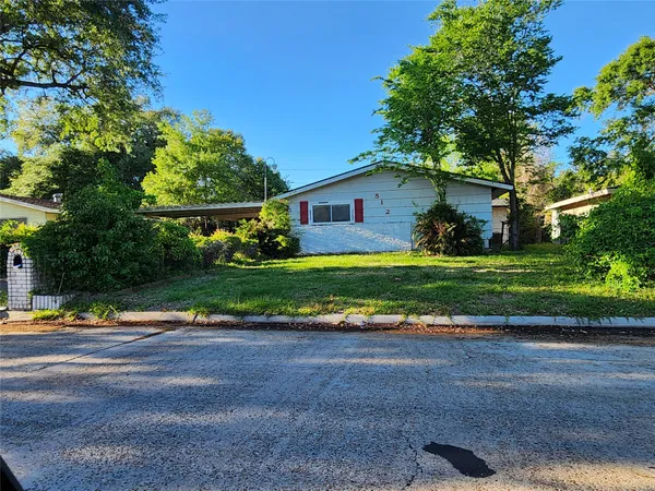 a view of a house with a yard and large tree