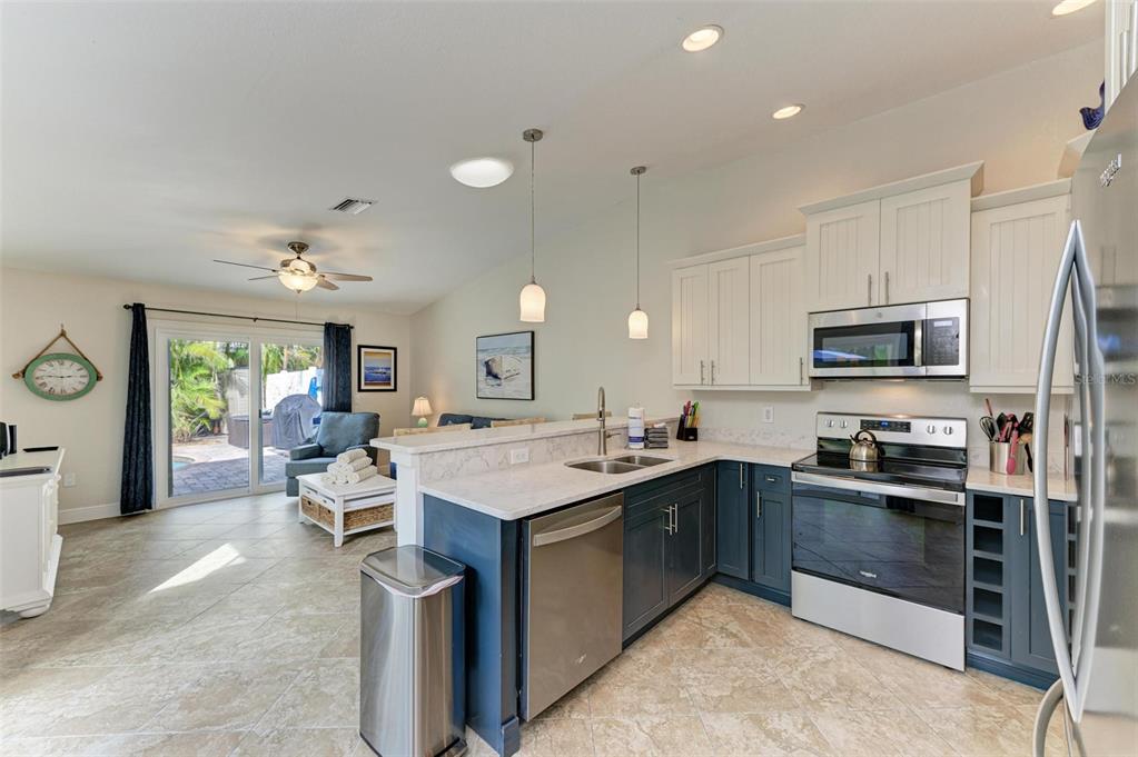 308 58th Street, Unit A Holmes Beach, FL 34217 - Photo 4 of 41 a kitchen with stainless steel appliances granite countertop a stove top oven a sink dishwasher a dining table and chairs with wooden floor