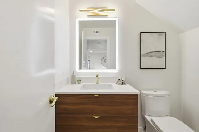 a bathroom with a sink vanity mirror and toilet