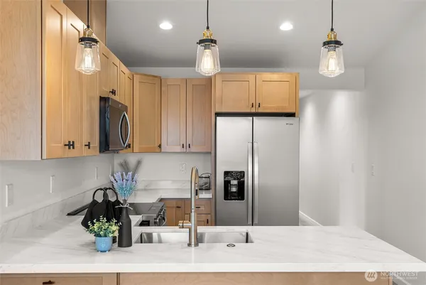 a kitchen with stainless steel appliances granite countertop a refrigerator a sink dishwasher and white cabinets