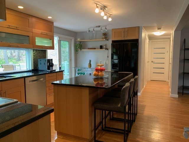 31 Hunnewell Street, Unit 31 Needham, MA 02494 - Photo 6 of 21 a kitchen with stainless steel appliances kitchen island granite countertop a table chairs in it and wooden floors