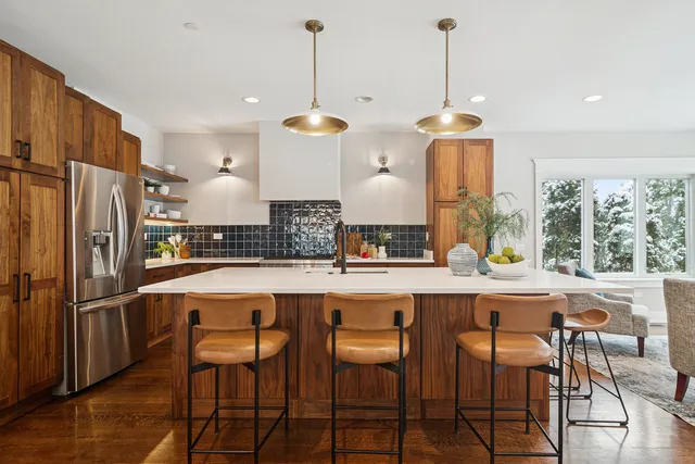 a kitchen with stainless steel appliances a dining table chairs sink and wooden floor