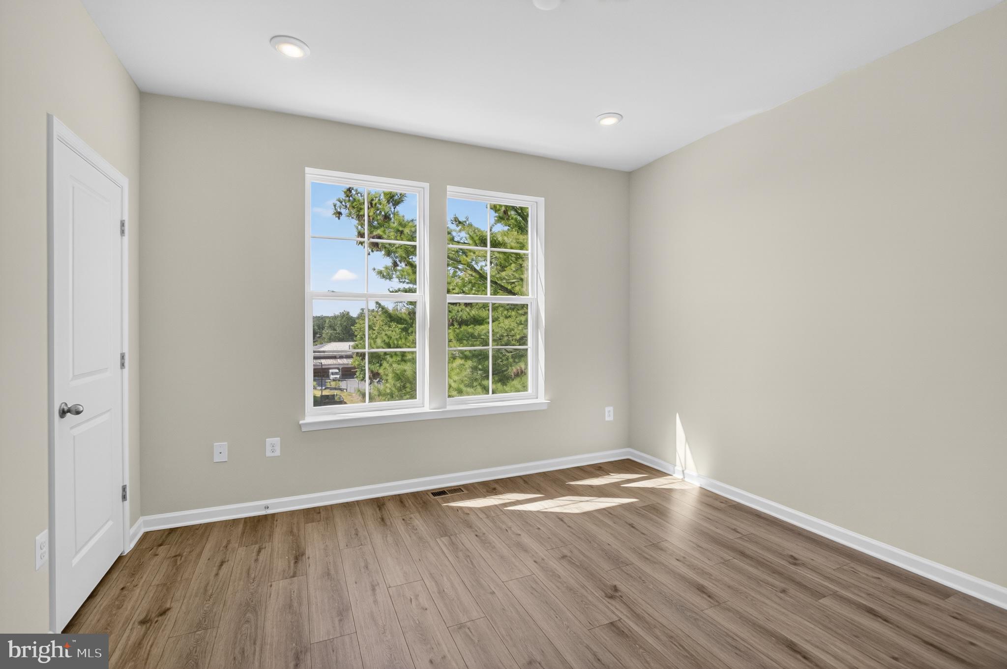 10046 Harper Vale Road Montgomery Village, MD 20886 - Photo 7 of 15 an empty room with wooden floor and windows