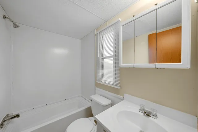 a bathroom with a bathtub shower sink vanity and toilet