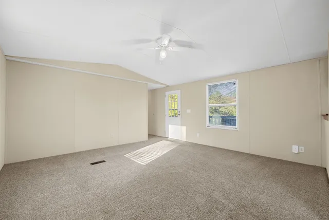 an empty room with windows and fan