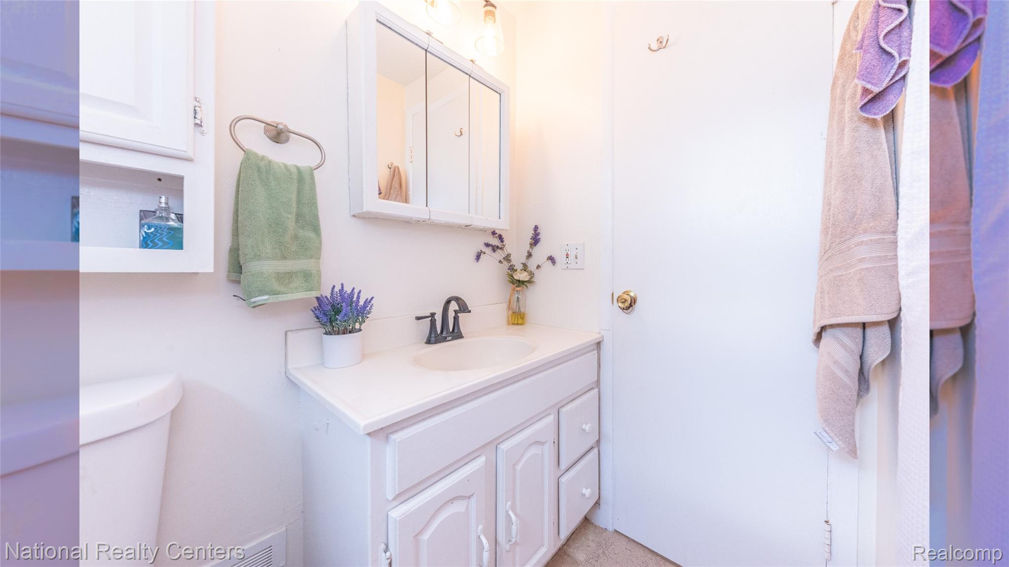 58191 8 Mile Road Northville, MI 48167 - Photo 37 of 57 Bathroom featuring a white vanity with integrated sink, a medicine cabinet with mirrored doors, and a toilet