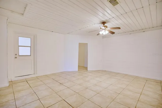 a view of an empty room and chandelier fan